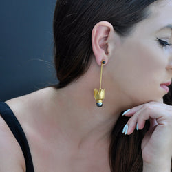 Gold tulip dangle earrings adorned with a black pearl